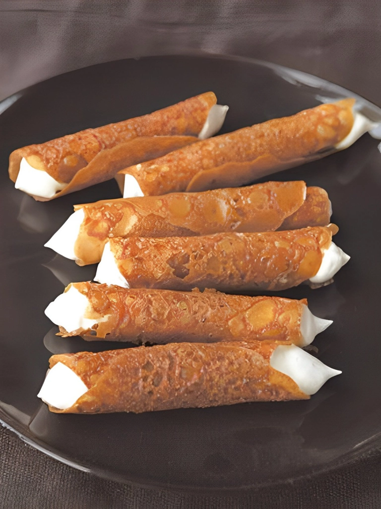 Met slagroom gevulde kletskoppen, knapperige koekjes opgerold en gevuld met romige slagroom, gepresenteerd op een donker bord.