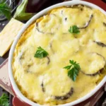 Een ovenschaal gevuld met traditionele Griekse moussaka, bestaande uit lagen aubergine, vlees en romige bechamelsaus, gegarneerd met verse peterselie en een goudbruine korst.