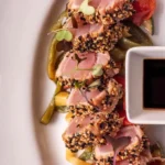 Tonijn tataki met zwart en licht sesamzaad op een ovale schaal en sojasaus