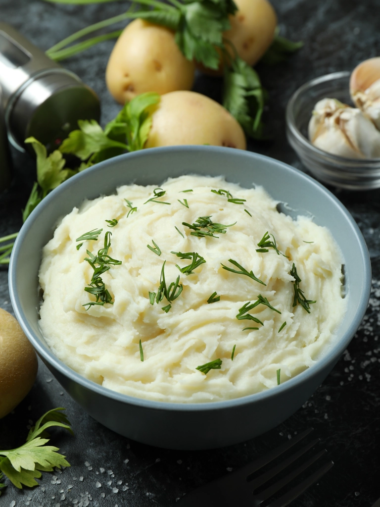 Aardappelpuree met knoflook en citroen in een mooi schaaltje op een donkere tafel.