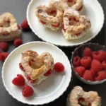 Bladerdeeghartjes op witte borden met rode frambozen